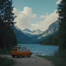 a yellow van parked next to a lake and mountains