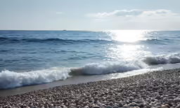 small waves lap onto some gray stones near the ocean