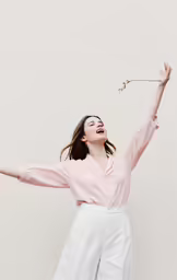 woman in pink shirt jumping with arms wide open