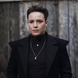 a man wearing a black jacket and chain necklace