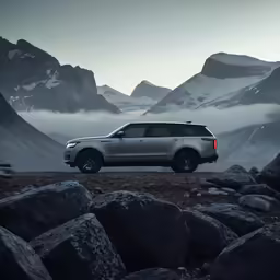 a suv is parked on a rocky area near the mountains