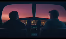 two men looking out of a car window at the sky
