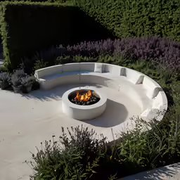 a fire pit in the middle of a garden with lavender plants