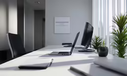 a table with two computer screens sitting next to a potted plant