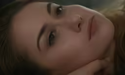 a woman lying on top of a bed next to her head