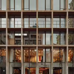 people are walking past a building with many windows