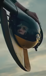 a man wearing a helmet looking into the side mirror of a helicopter