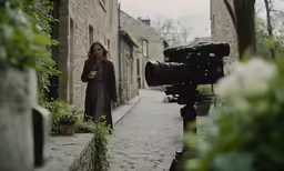 woman standing on walkway using a digital camera on the side walk