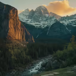 the view from a mountain looking down on a river running between tall snow covered mountains
