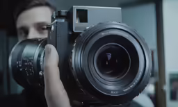 a young man taking pictures with an old camera