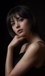 young asian woman with chin raised against dark background