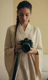 a woman in a kimono is holding a camera