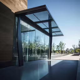 a building with glass on the outside, and another building with a large door with the sun peeking into it