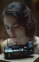 a girl looks down as she holds her camera