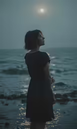 woman in dark dress looking at the sky on beach