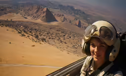 an female pilot in the air above a desert area