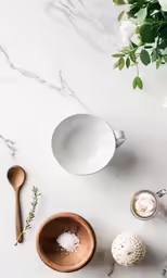 a bowl of food, a spoon and a cup of coffee on a marble table