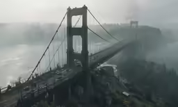cars travelling on a large bridge over a foggy water