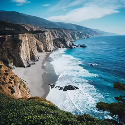 an ocean shore near a cliff and some water