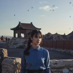 a young woman stands in front of the wall and pagodas