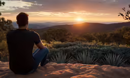 a man is sitting on top of a hill