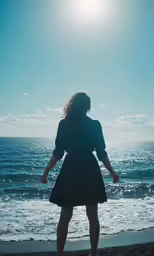 a woman in black is walking on a beach