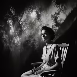 a woman sitting on a rocking chair under the moon