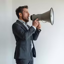 a man in a suit holding a megaphone up to his face