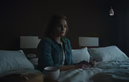 the woman sitting on her bed checking her phone