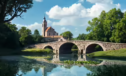 a stone bridge crossing a river next to a church