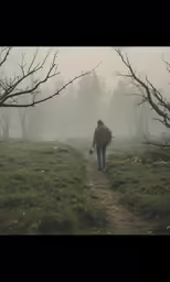 a man walks across a trail in the foggy woods