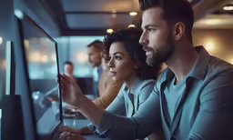 three young people sit in front of a computer screen while staring at it