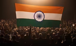 a large india flag is held high in a crowded audience