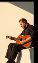 a man sitting on a ledge playing a guitar