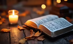 an open book sitting next to a lit candle