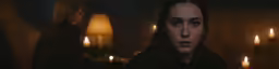 the woman is staring into the camera with lit candles