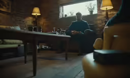 a man sitting in the corner next to a brick wall