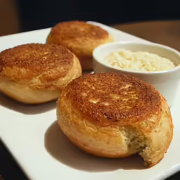 two bread rolls are on a white platter next to a small bowl of rice