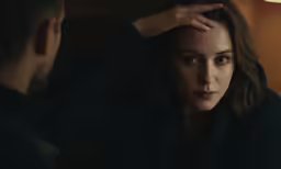 a woman sitting next to a man who is touching his forehead
