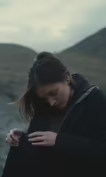woman standing in front of a mountain holding her hand to her chest