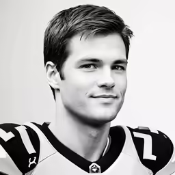a man with a football uniform on standing in front of a white wall