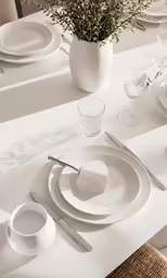 a table set for two with a white vase full of flowers