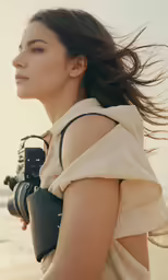 a woman is standing on a beach with a camera in her hand