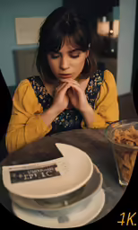the girl is sitting at a table by plates of food