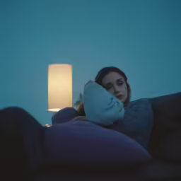 a woman is sitting on a couch wrapped up in blankets