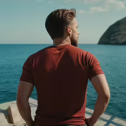 a man is looking at the ocean while he stares into the distance