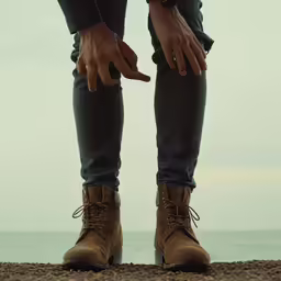 a man standing on the beach with his hand in his boot