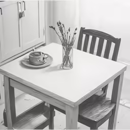 a black and white photo of a kitchen table with vase on it
