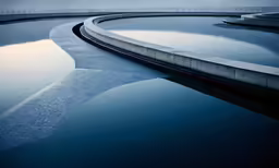 a curved concrete surface next to a body of water