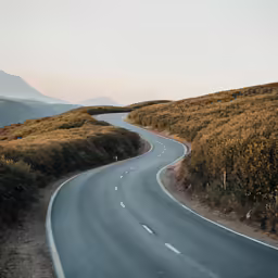 a curve in the road in a hilly field